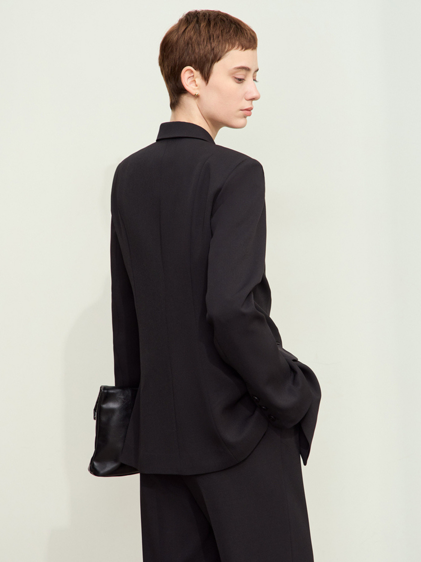 Bagvisning af sort blazer med lige fald og lommeflapper.