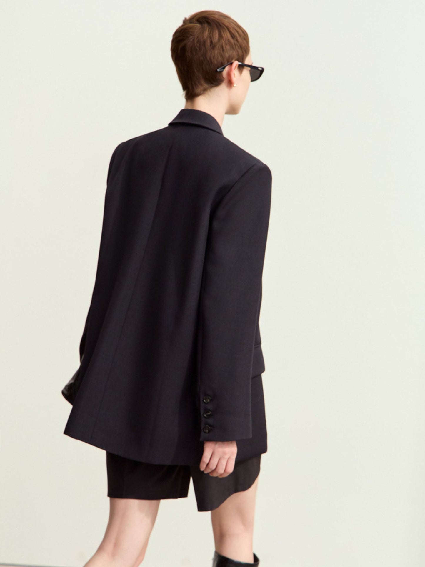 Bagvisning af sort blazer med løs pasform.