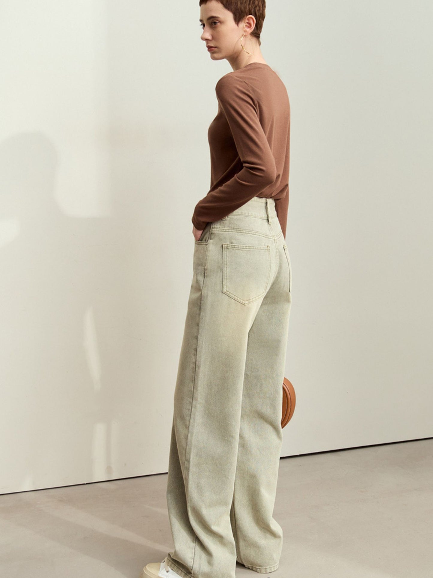 Model i brun top og lysegrønne jeans med vide ben og afslappet pasform.