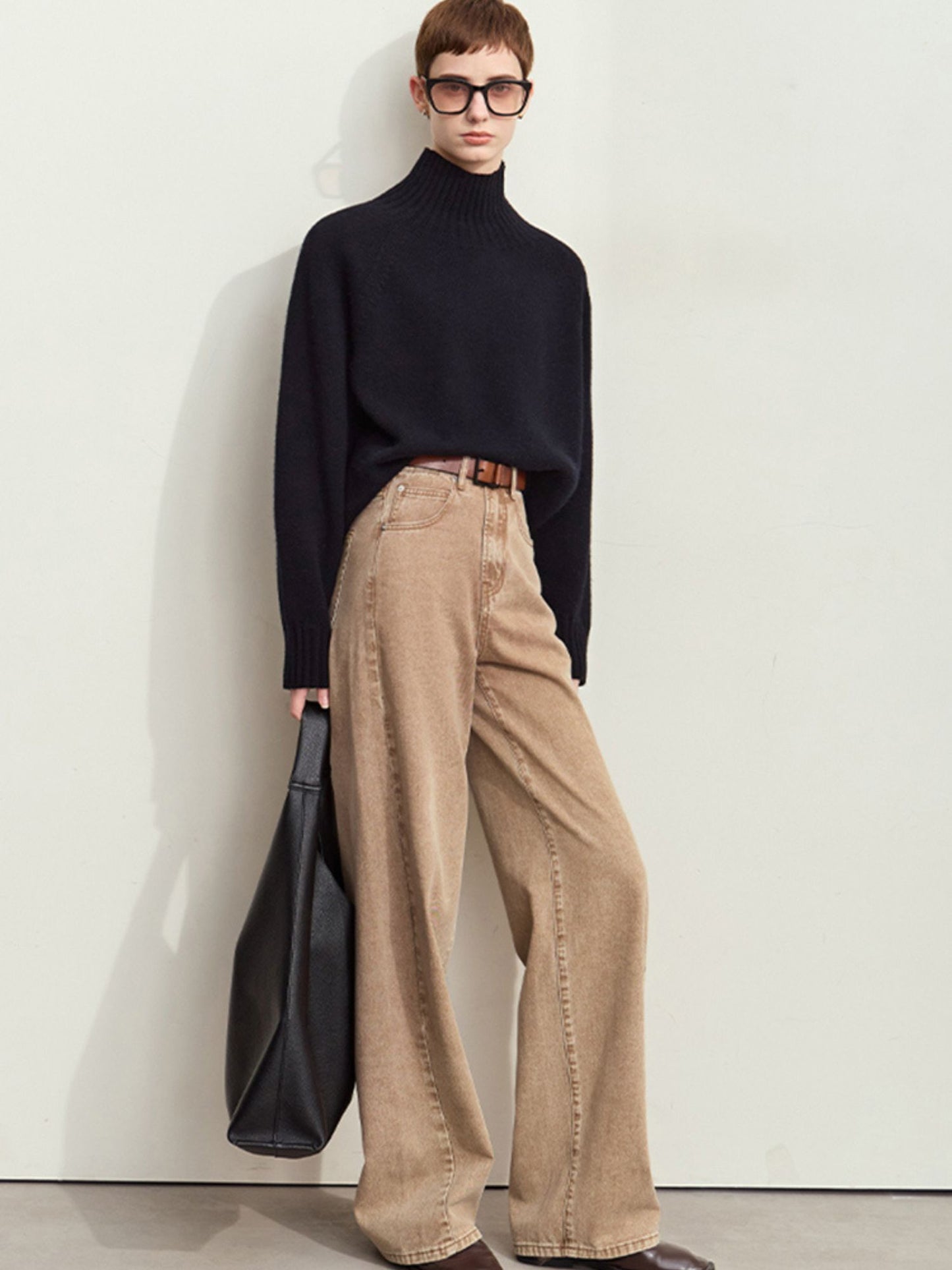Model iført sort trøje og brede beige fløjlsbukser med høj talje.