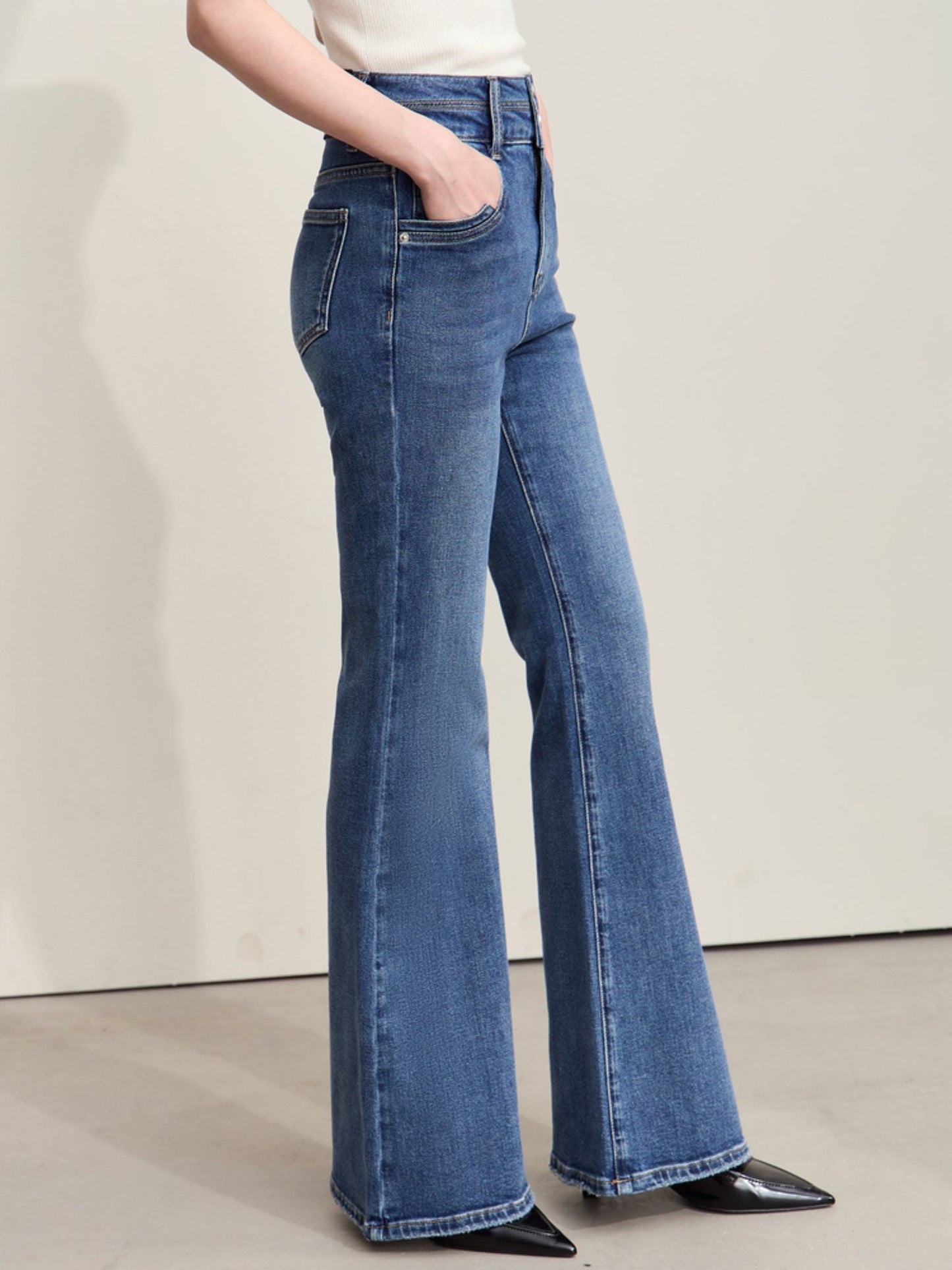 Sidevisning af blå jeans med høj talje og let svaj ved anklerne.