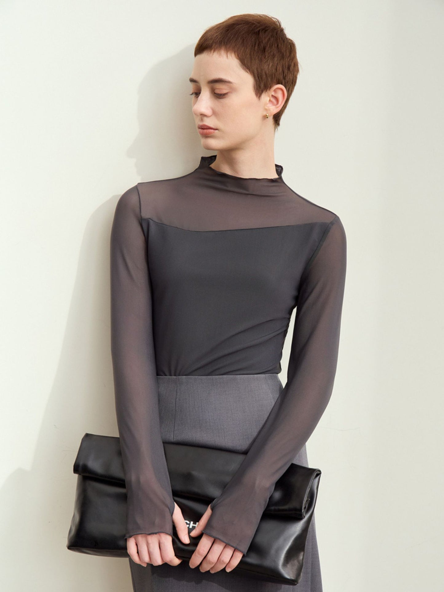 Bagfra visning af brun bluse med tætsiddende pasform og høj hals.