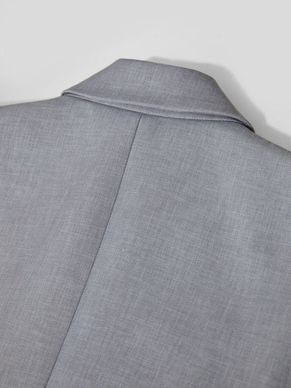 Detaljebillede af knaphul og syninger på grå blazer.