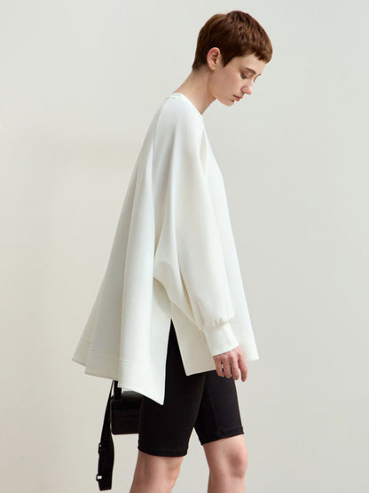 Model i hvid sweatshirt vendt let mod siden, med hånden løftet.