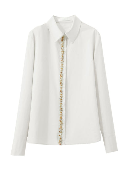 Hvid skjorte lagt fladt, viser perleknapper og klassisk krave.