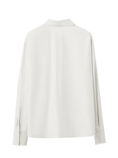 Bagvisning af hvid skjorte lagt fladt, lange ærmer og lige snit.