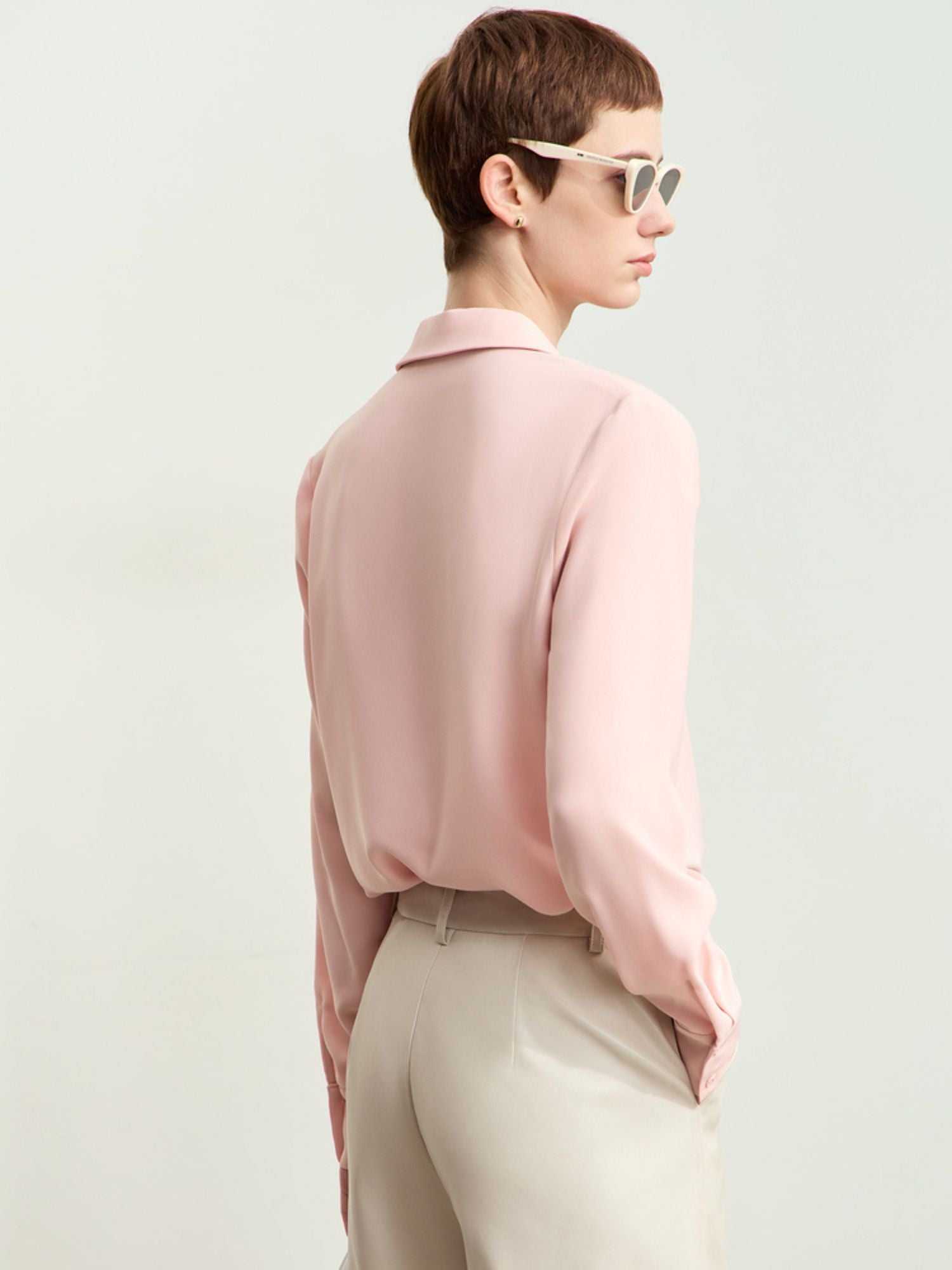 Bagfra visning af rosa skjorte med løstsiddende pasform og lange ærmer.