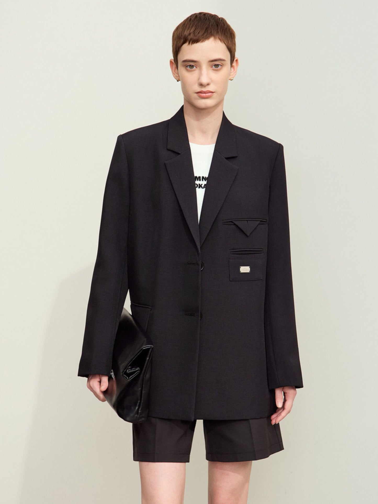 Sort blazer med markerede skuldre og dobbeltradet knaplukning.