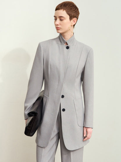 Model iført lysegrå blazer med ståkrave og sorte knapper.