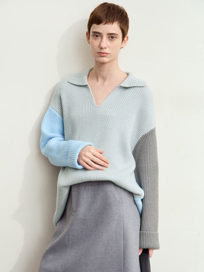 Model i farveblok-strik i lyseblå og grå med krave og lange ærmer.