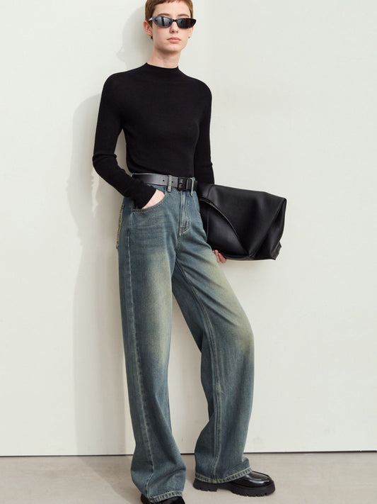 Model iført sorte top og løse mørkeblå jeans med vaskede detaljer.