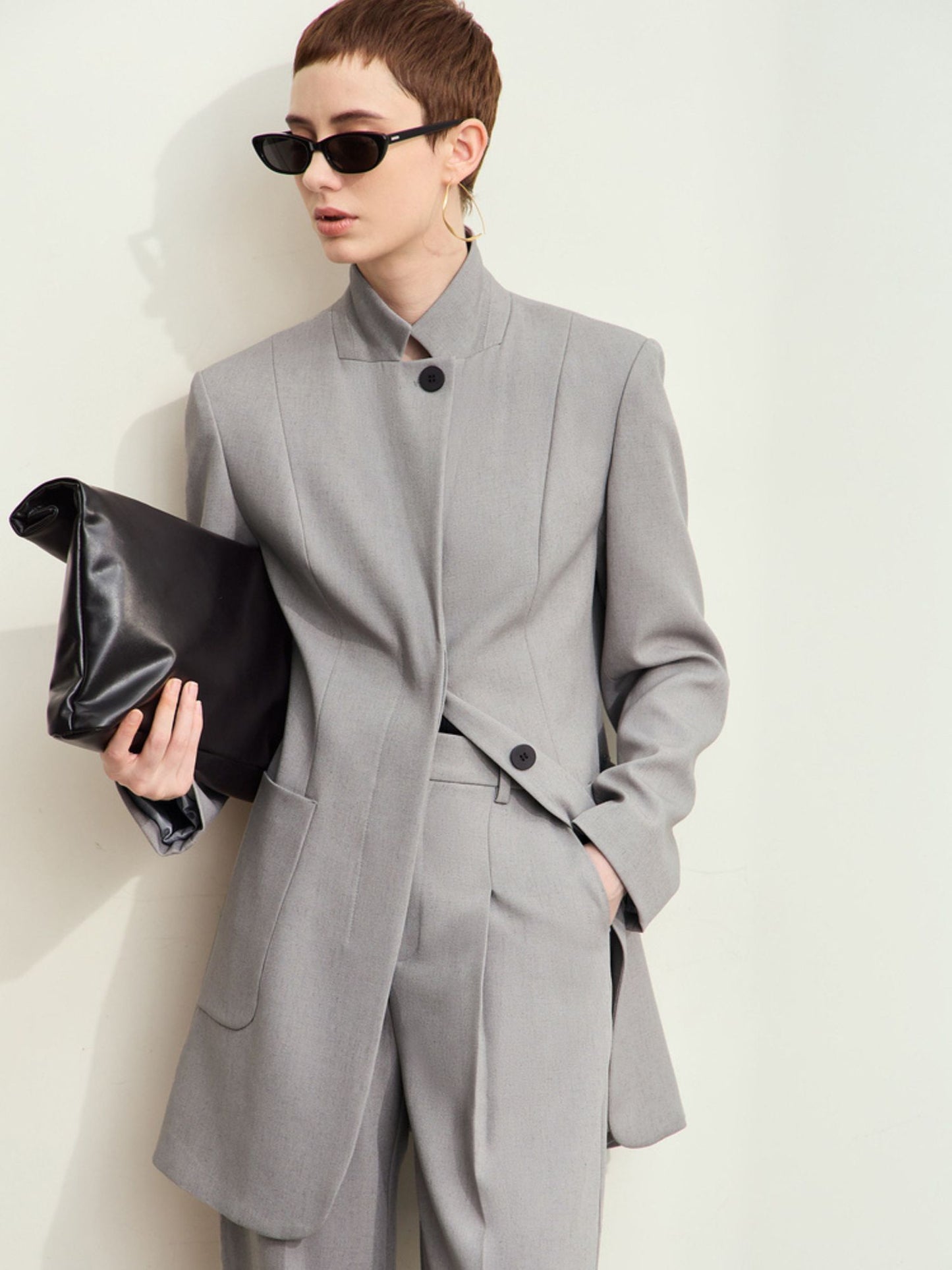 Lysegrå blazer båret med solbriller og sort clutch.