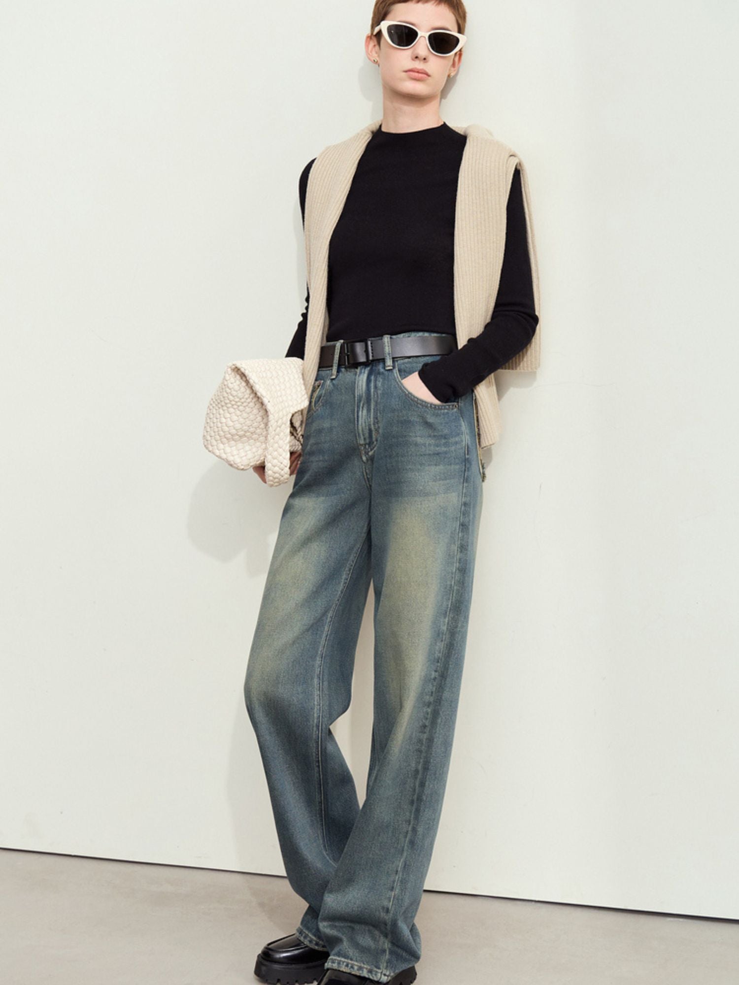 Jeans stylet med sort top og solbriller, set forfra.