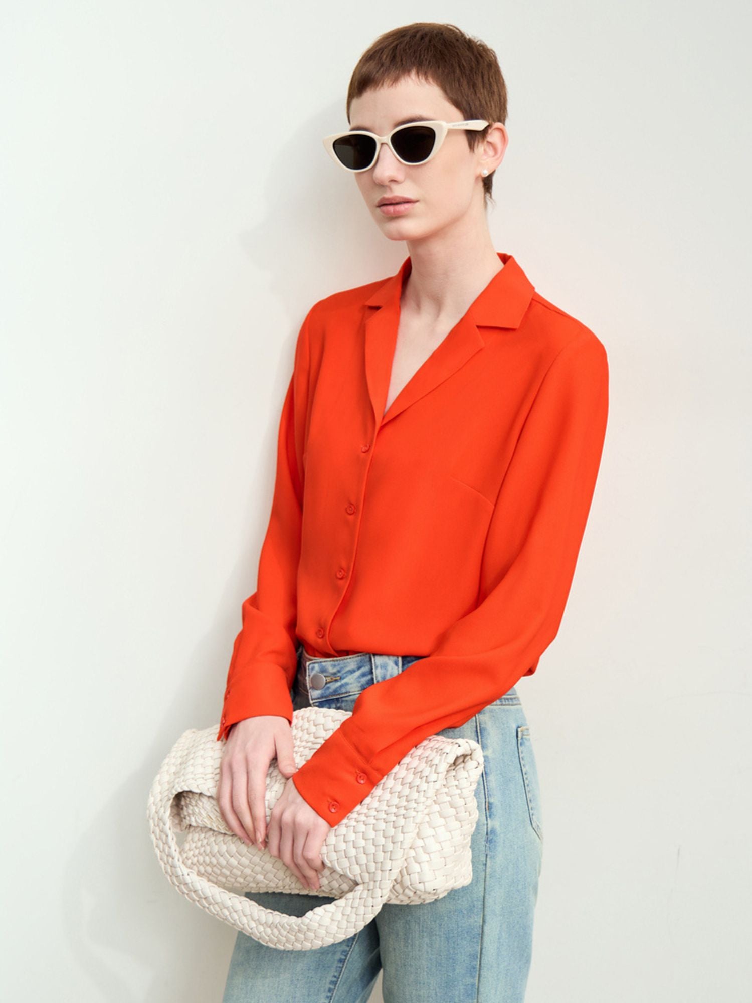 Rød-orange skjorte med solbriller og jeans, model ser til siden.