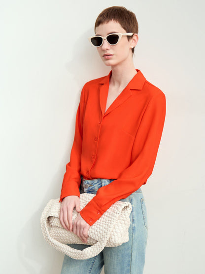 Rød-orange skjorte med solbriller og jeans, model ser til siden.