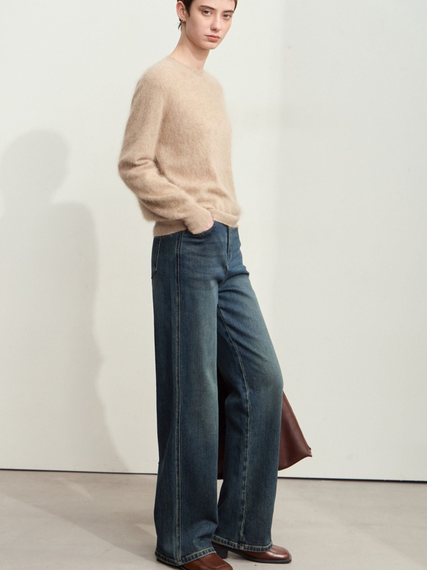 Sidevisning af mørkeblå jeans stylet med beige sweater og flade sko.