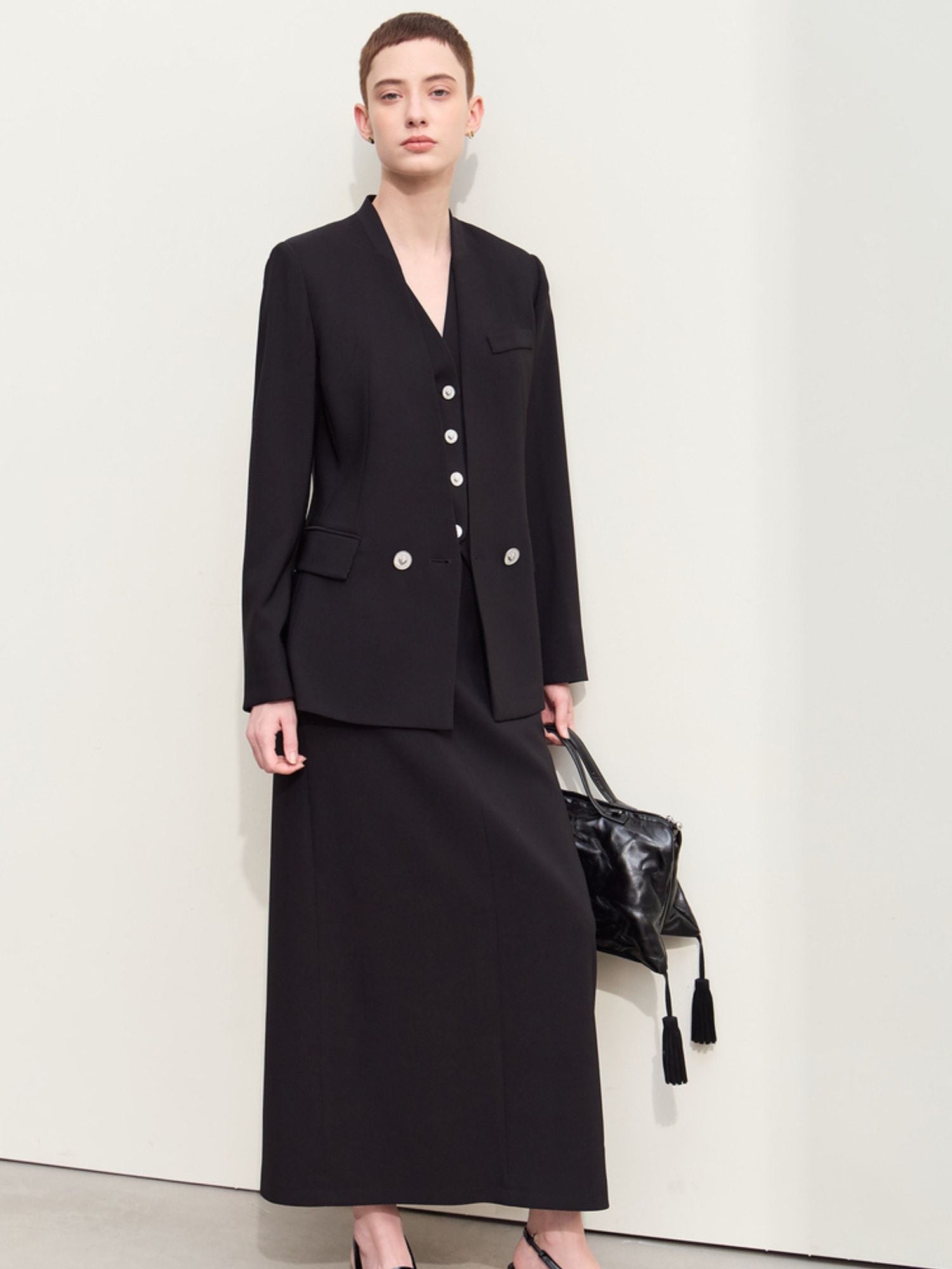 Sort blazer med v-udskæring, båret med taske i hånden.