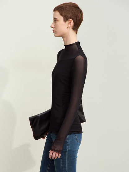 Sort mesh-bluse set i profil, model holder clutch og kigger væk.