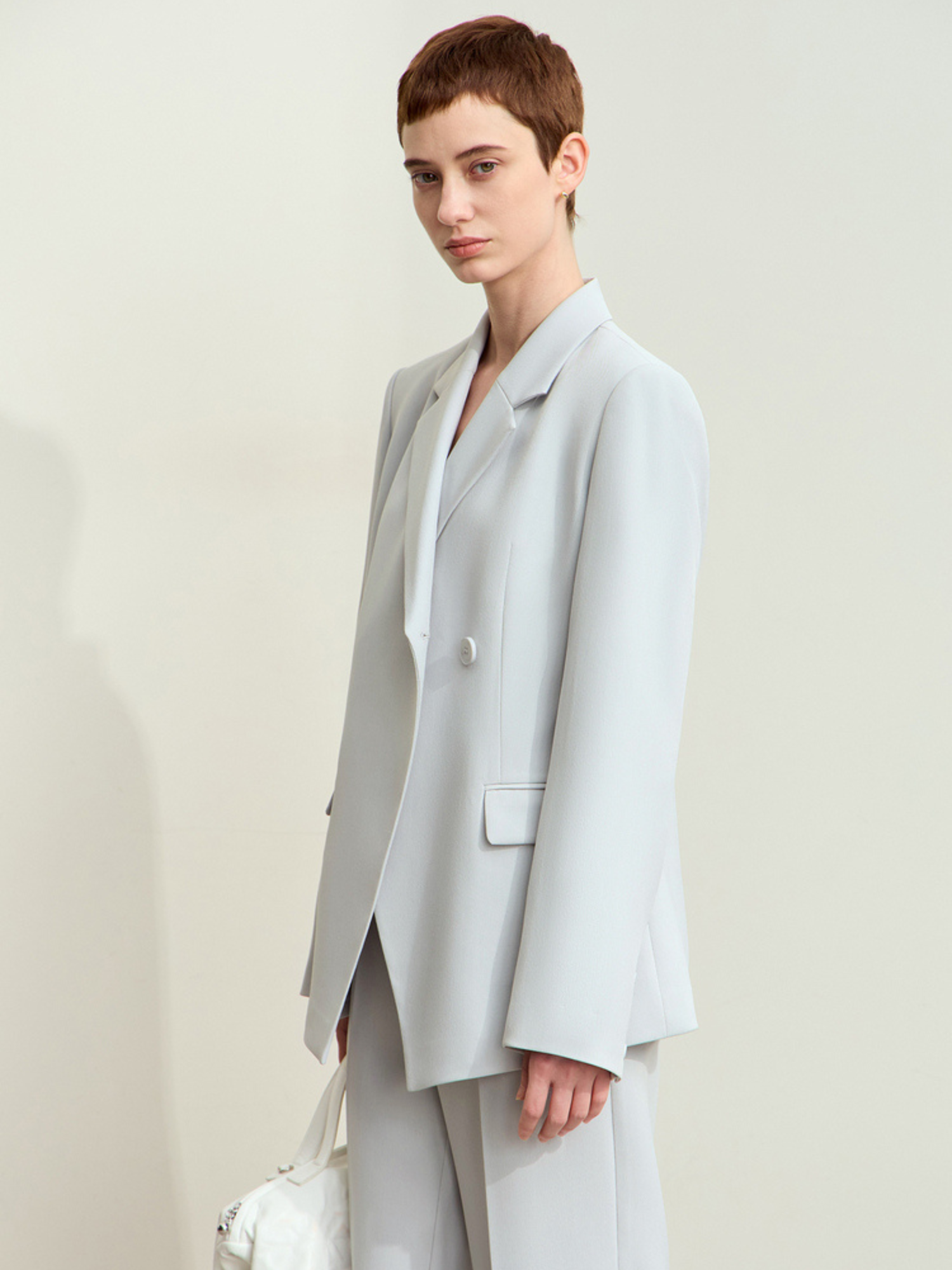 Sidevisning af lyseblå blazer med lige snit.