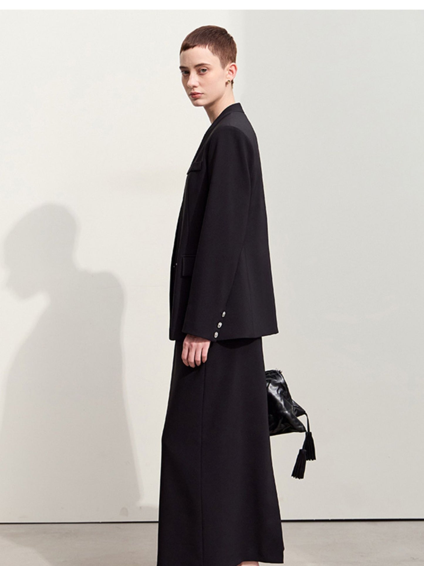 Sidevisning af sort blazer med dybe lommer og elegant fald.