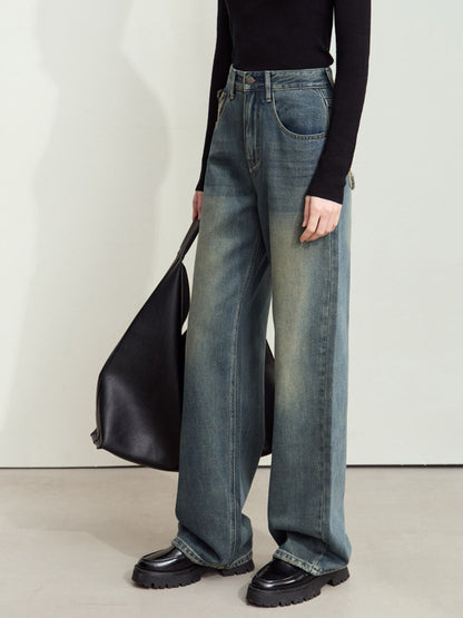 Model bærer mørkeblå jeans med brede ben og stor sort taske.