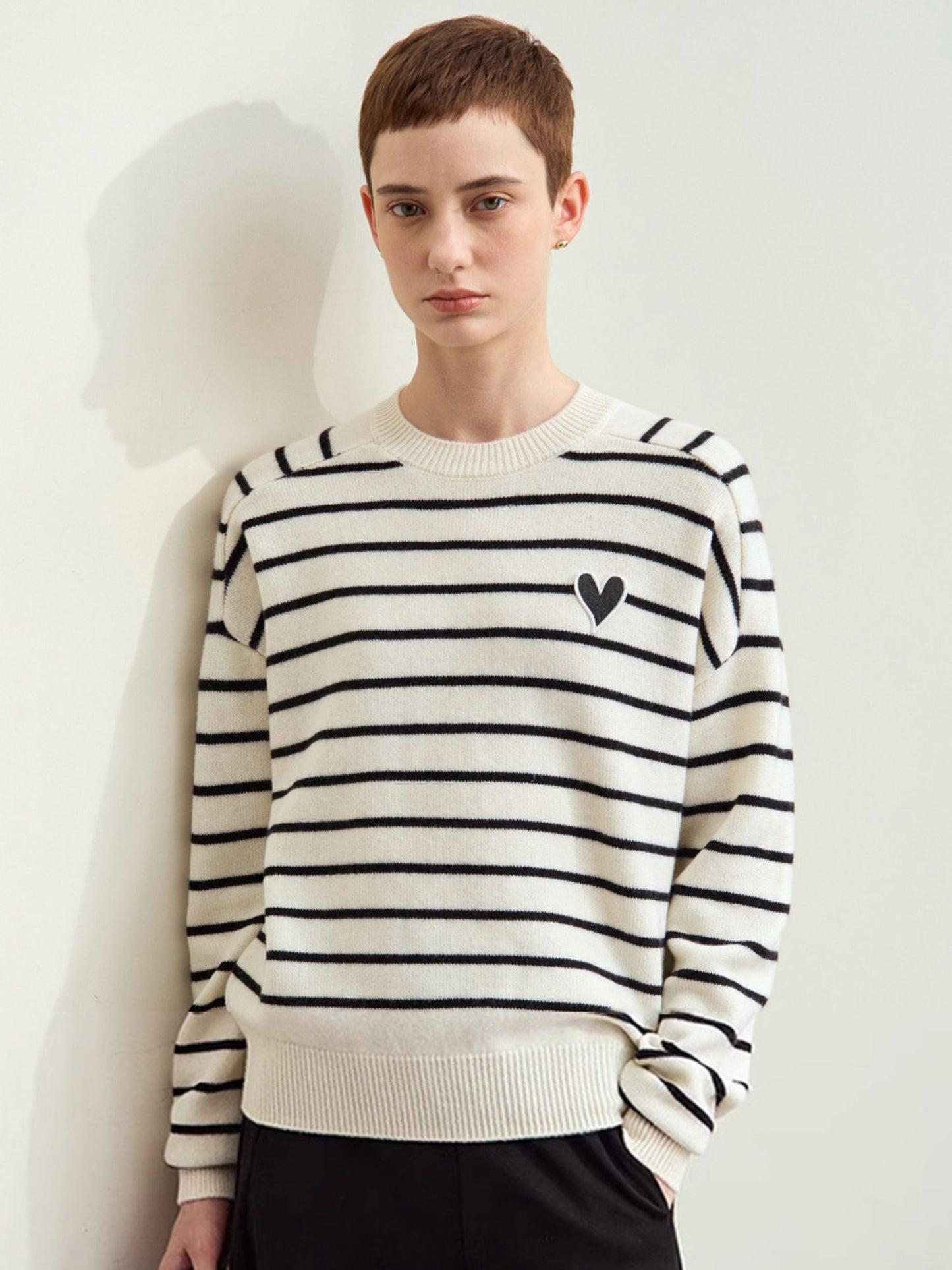 Nærbillede af brunt hjertebroderi på beige og hvid stribet sweater.