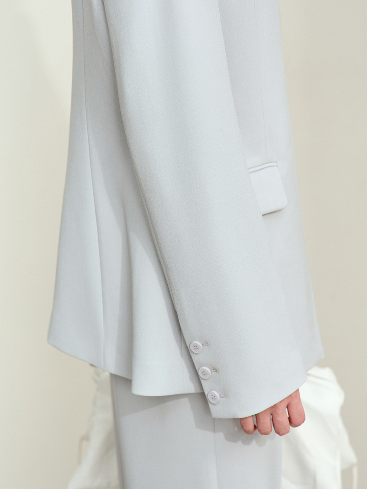 Bagvisning af lyseblå blazer med slidsdetalje.