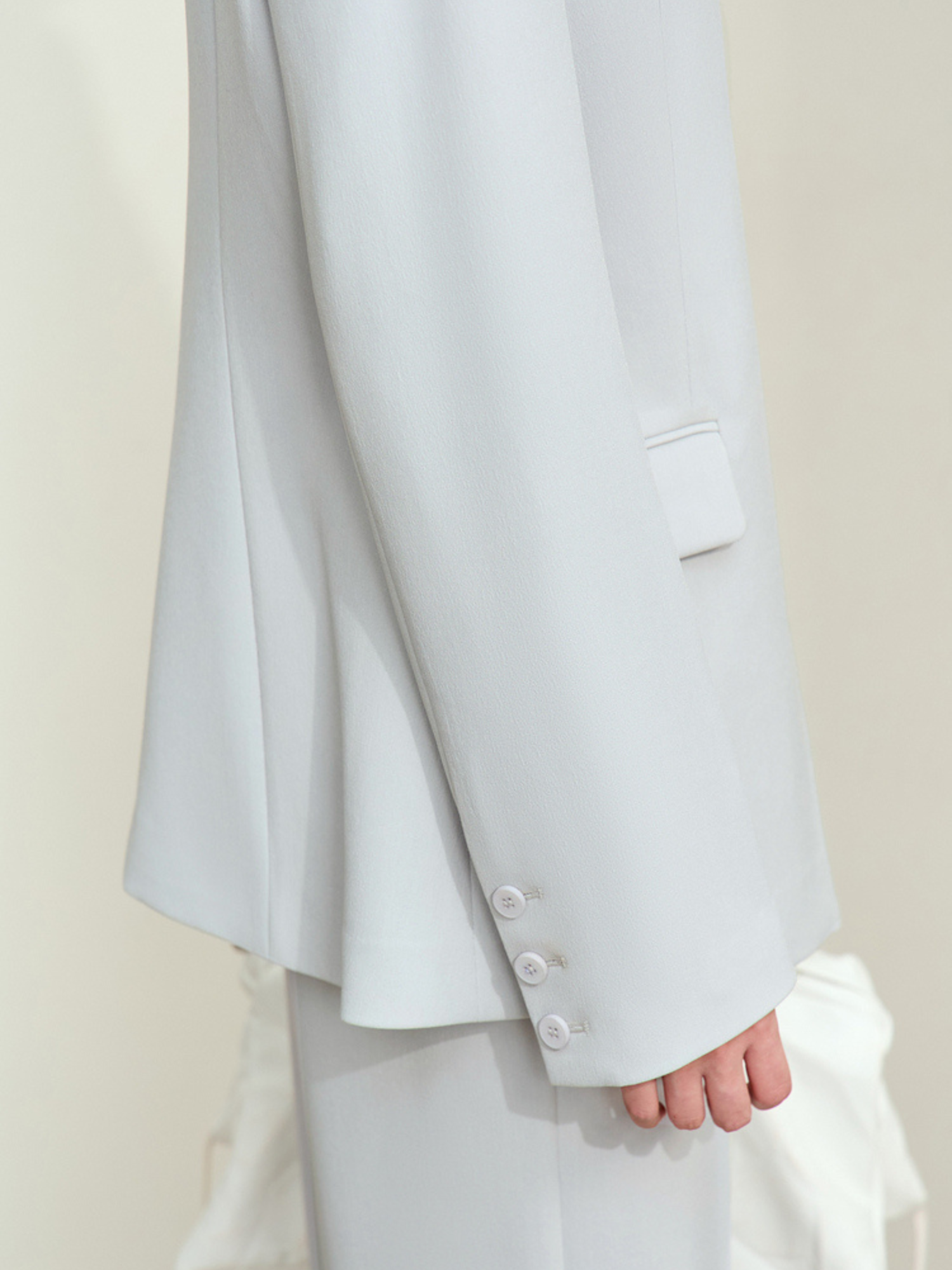 Bagvisning af lyseblå blazer med slidsdetalje.