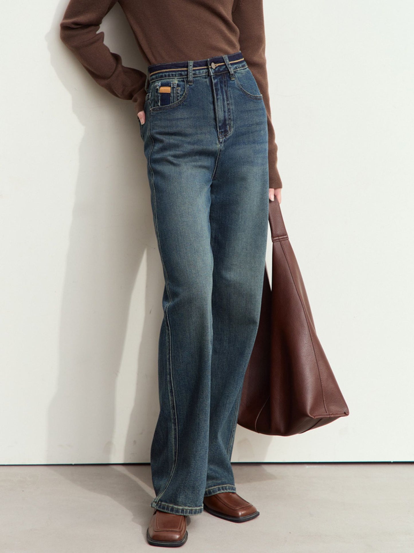 Nærbillede af front og lomme med guldmærke på mørkeblå jeans.