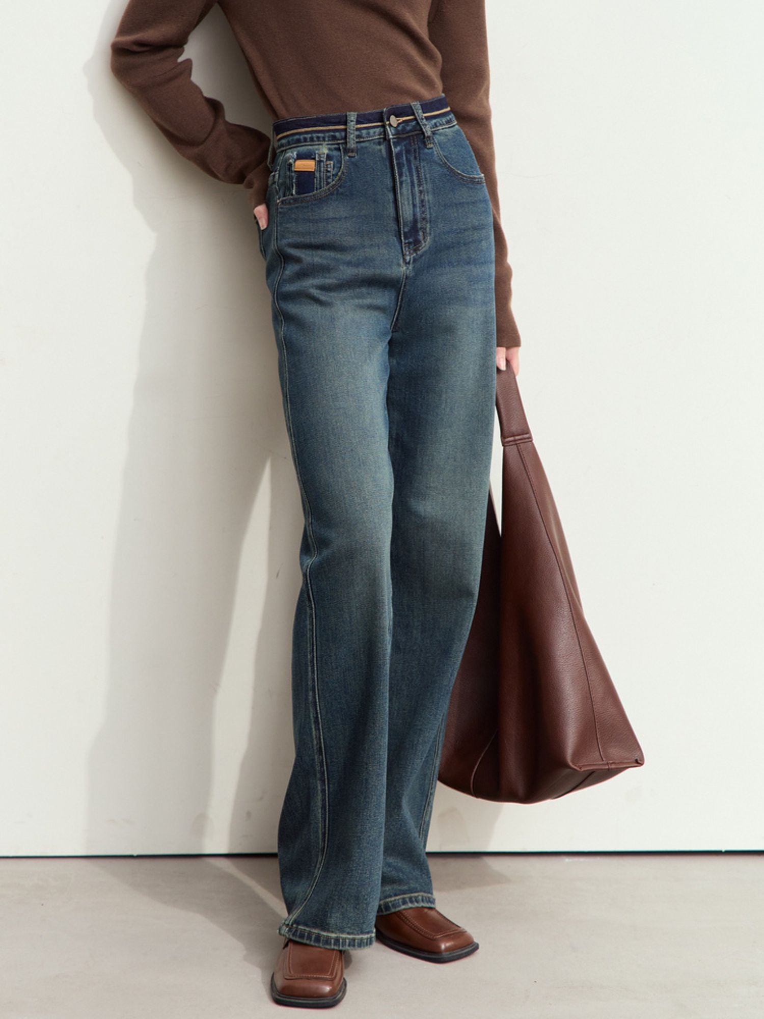 Nærbillede af front og lomme med guldmærke på mørkeblå jeans.