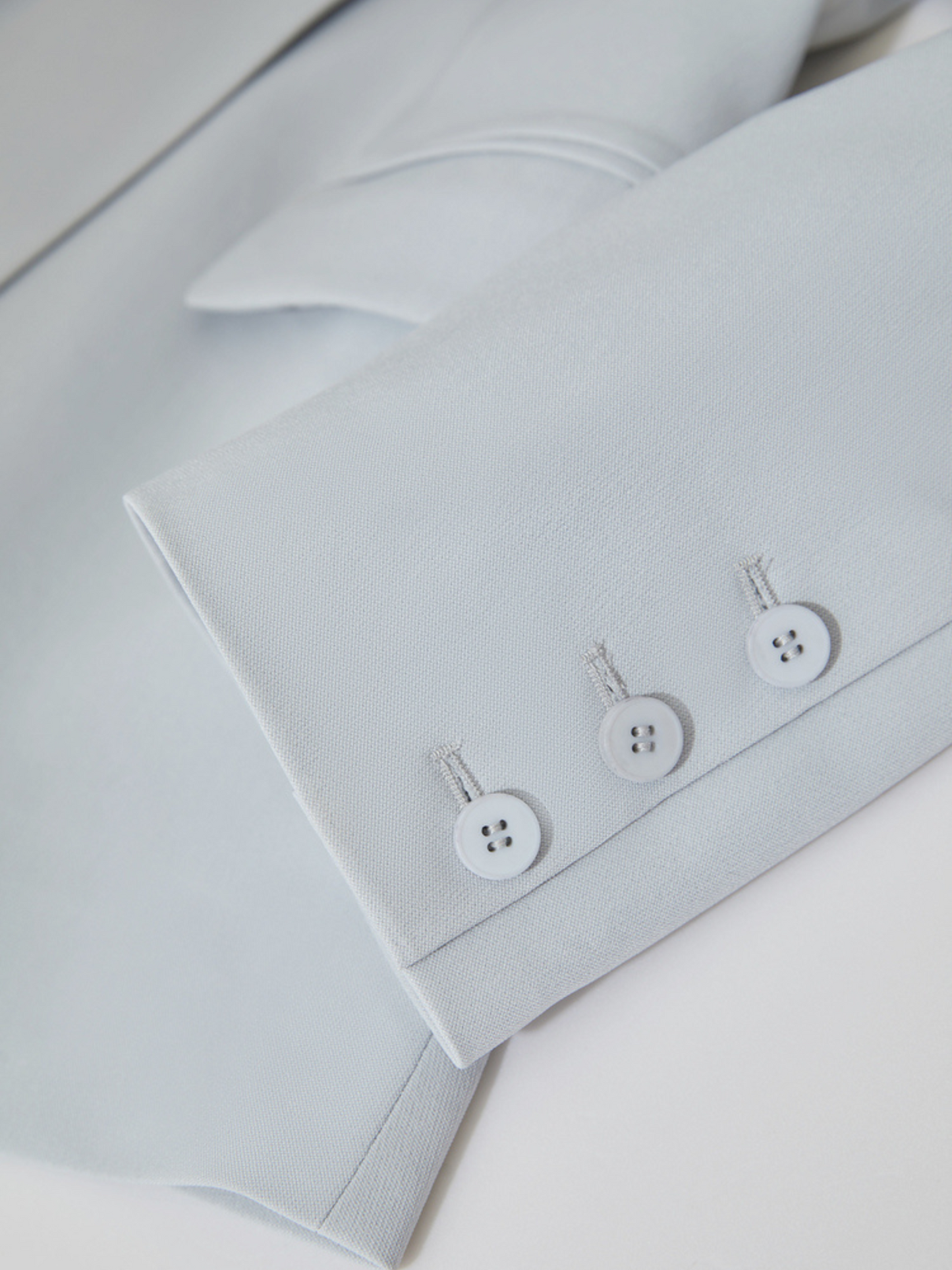 Mørk baggrundsbillede af blazer og bukser i lyseblå.