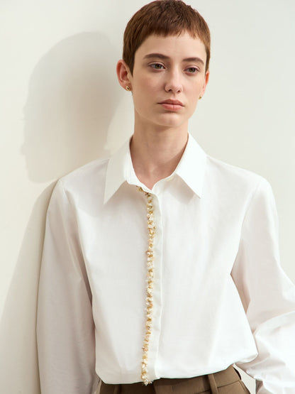 Skrå vinkel af model i hvid skjorte og brun nederdel, står op ad væg.