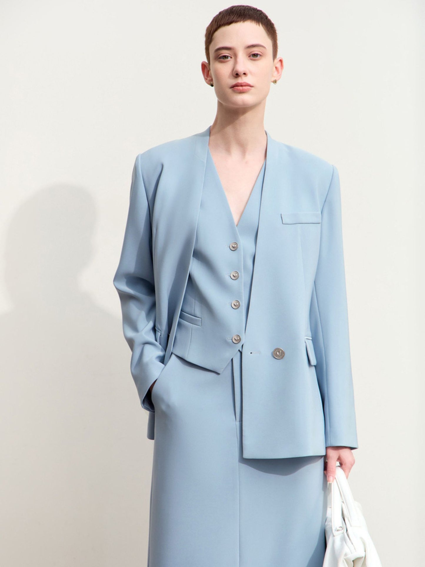 Model iført lyseblå blazer med v-udskæring og to knapper.