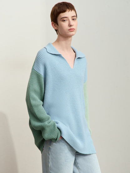 Model sidder i lysegrøn og blå striktrøje med hånd på hovedet.