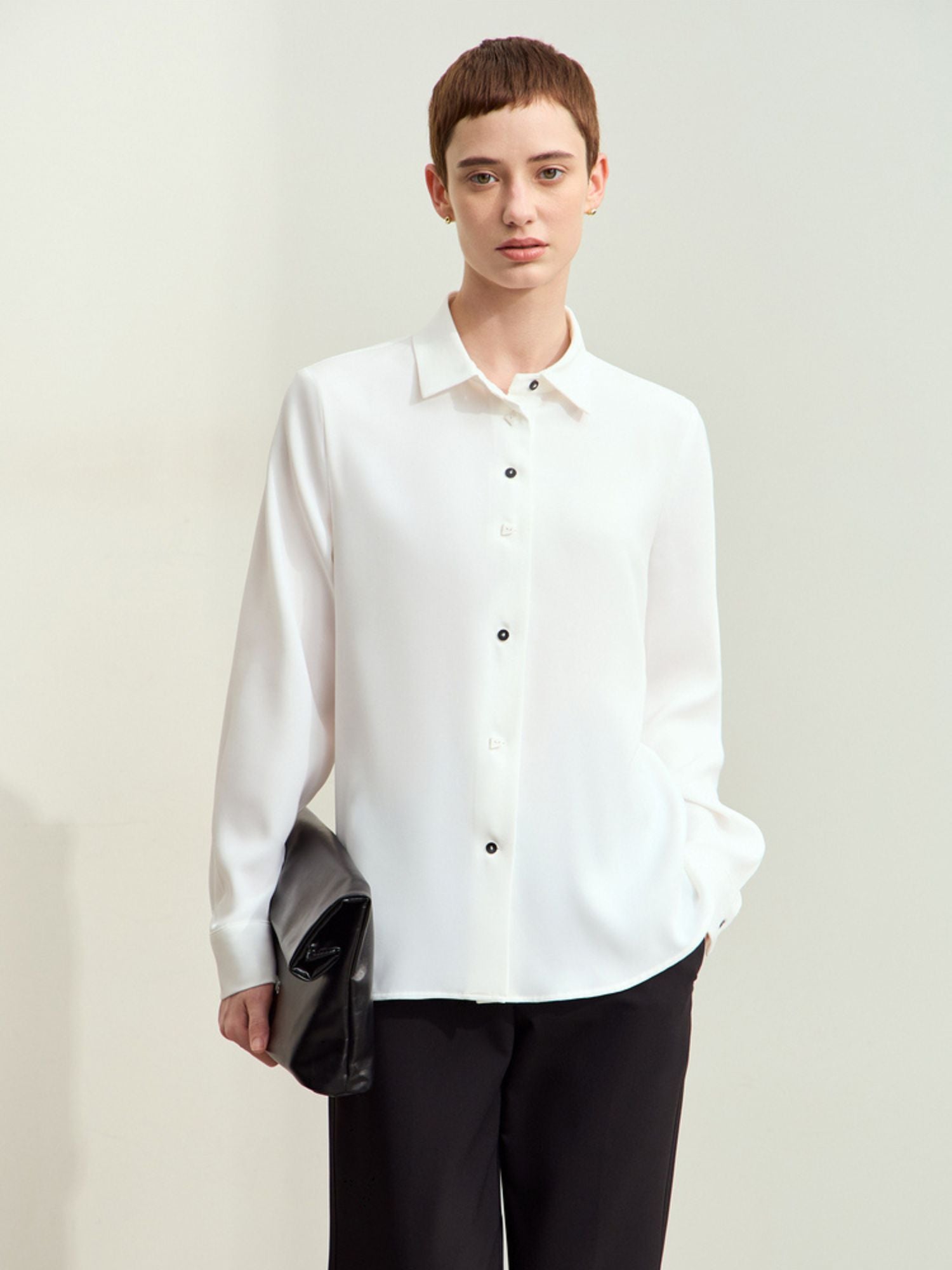 Frontvisning af hvid skjorte med lange ærmer, bæres løst af model.