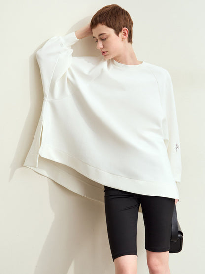 Model i hvid sweatshirt med asymmetrisk snit og sorte shorts.