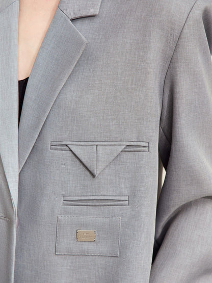 Bagvisning af grå blazer båret med sort nederdel.